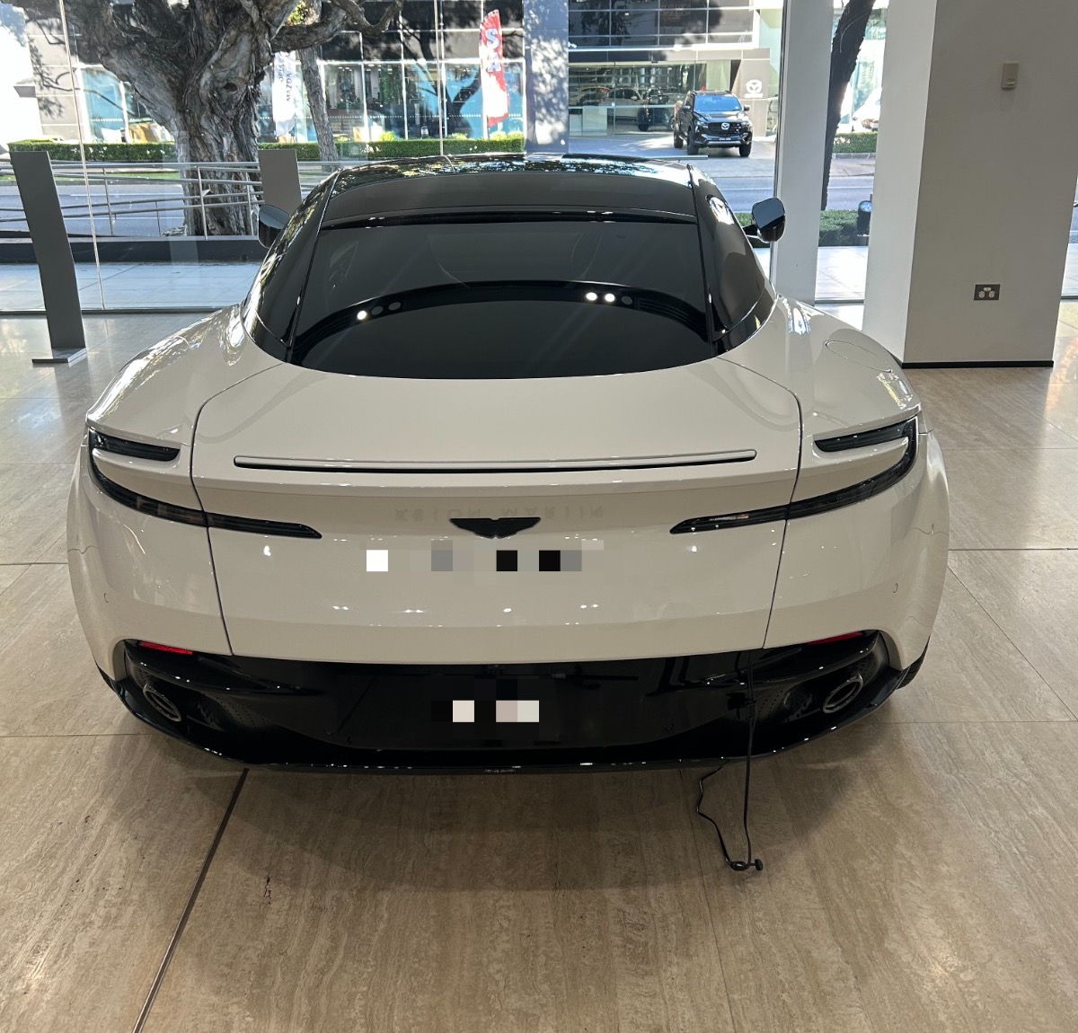 A DB12 in white, photographed by us at Aston Martin Sydney; number plate blurred per our privacy policy. Photography: Queen of Cars.